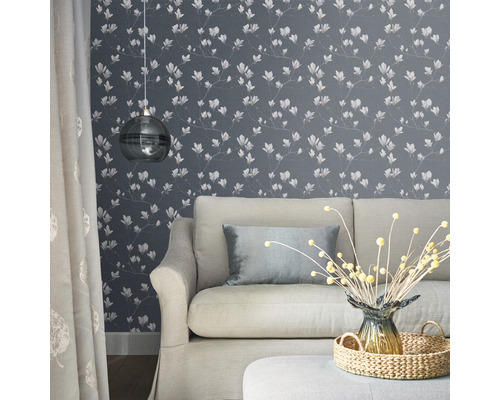 Vardagsrum med soffa, lampa och blommig tapet