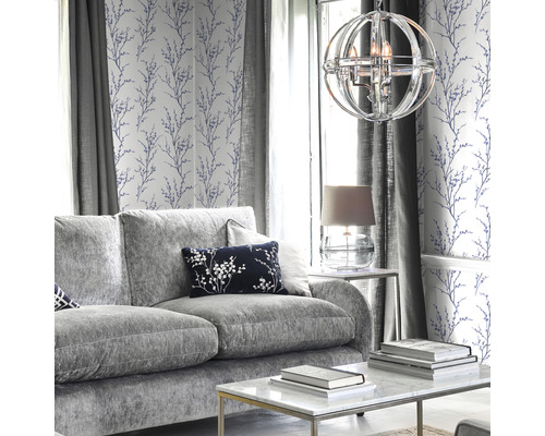 Vardagsrum med grå soffa, soffbord, lampa och tapet med blommönster