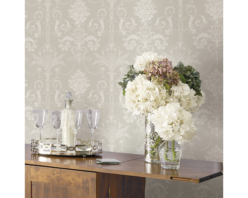 Tapet med blommönster ovanför ett träskåp med blomsterarrangemang och dryckestillbehör