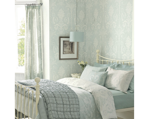 Ljust sovrum med säng, tapet med mönster, gardiner och lampa