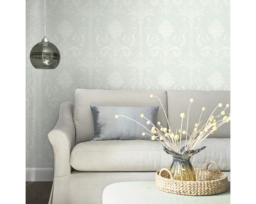 Vardagsrum med mönstrad tapet, soffa, kudde, bordsdekoration och hänglampa