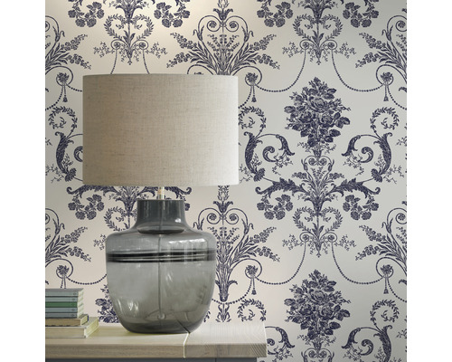 Dekorativt rum med en bordslampa framför en blommig tapet.