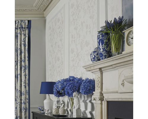 Vardagsrum med blommig tapet, gardiner med blommönster och dekorativa tillbehör