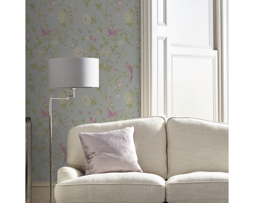 Miljöbild med tapet med fågel- och blomstermotiv, soffa och golvlampa