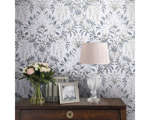 Dekorativt rum med blommig tapet, bordslampa, blombukett och fotoram