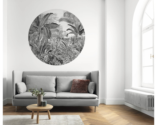 Vardagsrum med grå soffa, träbord, matta och väggdekor med djungelmotiv