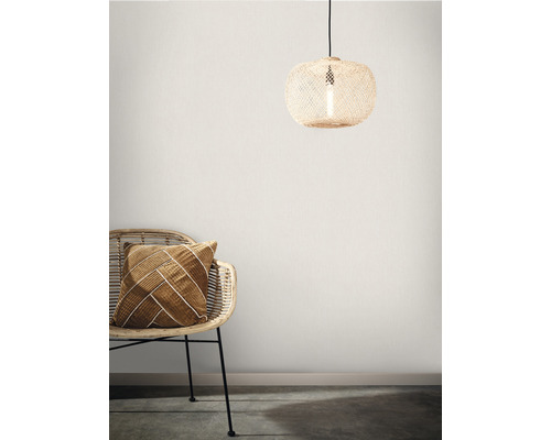 Dekorativ scen med taklampa i rotting och fåtölj med kudde