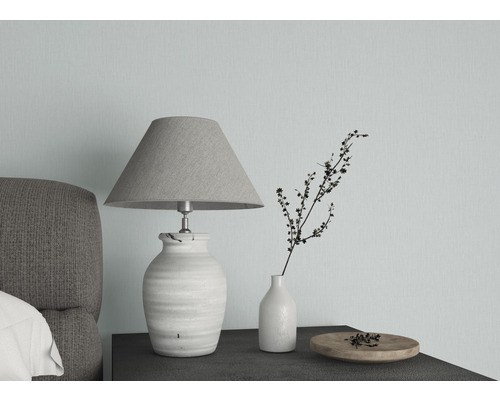 Dekorativ bordslampa bredvid vas och skål på ett nattduksbord.