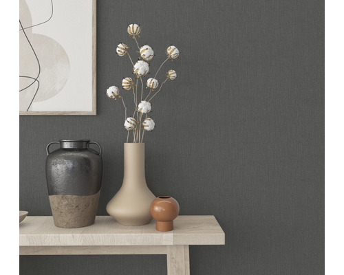 Dekorativa vaser och växter på ett ljust träbord framför en grå vägg.