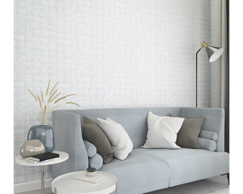 Ljust vardagsrum med soffa, kuddar, sidobord och mönstrad tapet