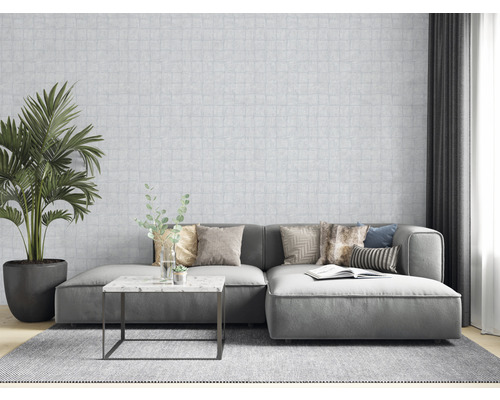 Vardagsrum med soffa, kuddar, bord, krukväxt och mönstrad tapet