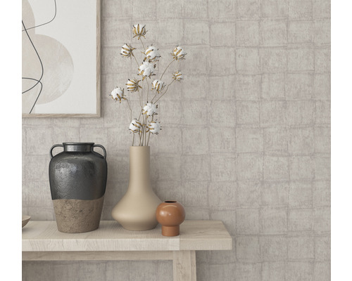 Närbild av olika vaser och dekorativa element på ett träbord framför en mönstrad vägg.