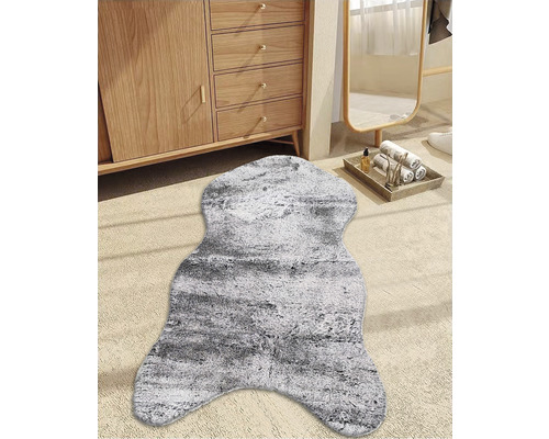 Dekorativ gråvit fuskpäls framför ett träskåp och en spegel