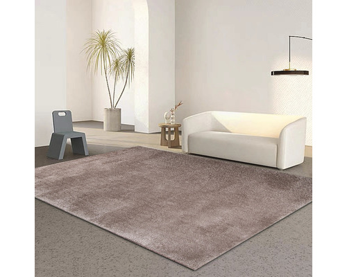 Vardagsrum med en brun matta, en vit soffa och en grå stol.