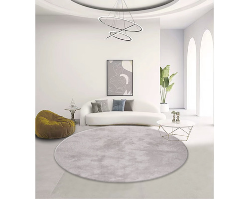 Ljust vardagsrum med soffa, fåtölj, soffbord, krukväxt, lampa och rund matta