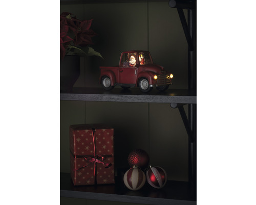Dekorativ julbil med jultomte och present på en hylla
