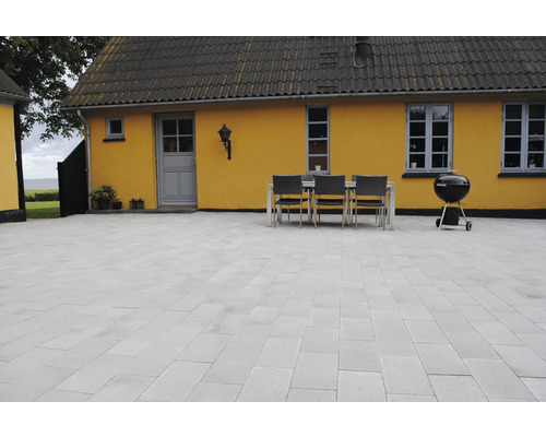 Uteplats med gatstenar, matbord och grill
