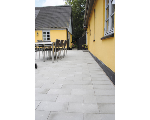 Uteplats med rektangulära betongstenar, sittgrupp och byggnader