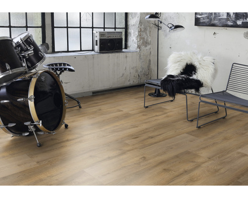 Interiörbild av ett rum med laminatgolv, trumset, stol och radio
