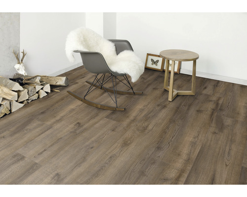 Interiör med golvbeläggning i träoptik, gungstol med päls, sidobord och dekoration.