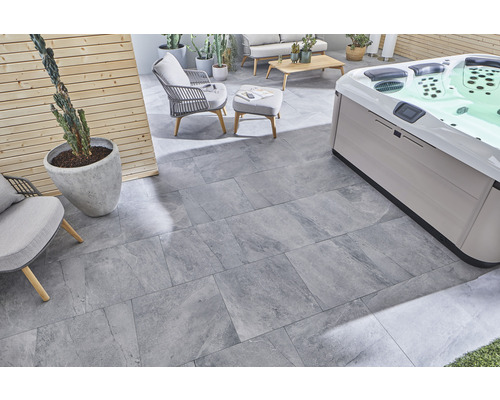 Terrass med grå stengodsplattor, bubbelpool och sittmöbler