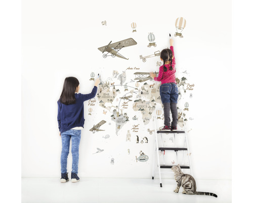 Två barn målar en väggdekal med en världskarta med flygplans-, luftballongs- och djurmotiv.