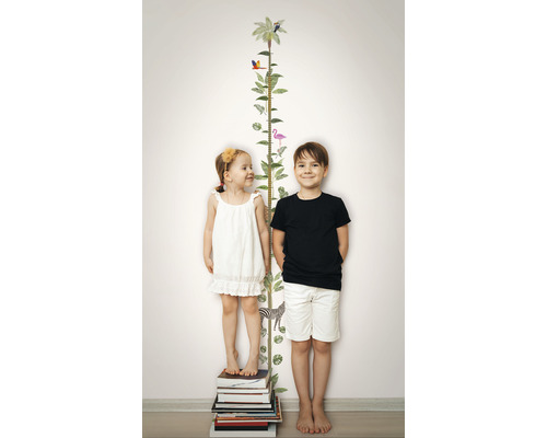 Barn står bredvid ett tillväxtdiagram med djurmotiv på en vägg