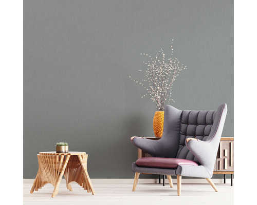 Vardagsrumsscen med fåtölj, sidobord, vas och matchande väggtapet