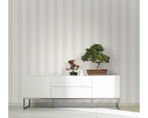 Rumsvy med randig tapet, vit skänk och bonsaiträd som dekoration