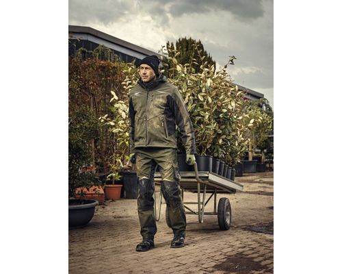 Man i arbetskläder skjuter en skottkärra med växter