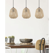 Tre flätade hänglampor i rotting ovanför ett matbord.