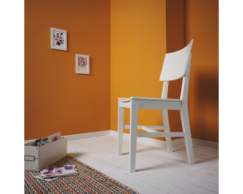 Ljust rum med trästol, bilder och förvaringslåda