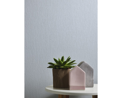 Närbild av en tapet med fin textur, kombinerad med en suckulent i kruka och dekorativa hus på ett bord