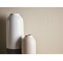 Närbild av två vaser mot en beige tapet med textur.