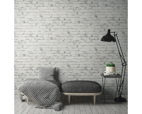 Dekorativt vardagsrum med tapet med tegelmönster, sittmöbel, golvlampa och sidobord.