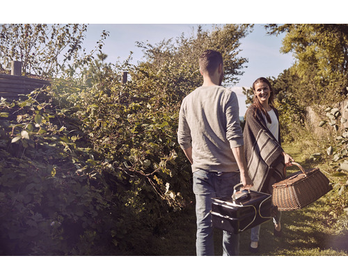 Ett par med picknickkorg och kylväska i naturen
