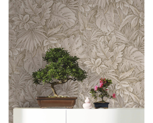 Två bonsaiträd på ett skåp framför en vägg med bladmotivtapet.