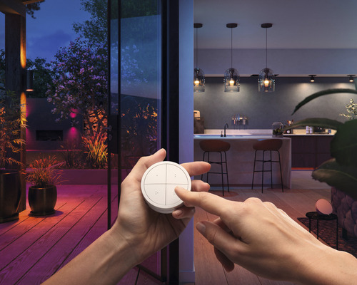 Scen med en person som använder en ljusströmbrytare framför en upplyst uteplats och ett inre kök
