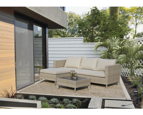 Uteplats med rottingsoffa, soffbord och grusgolv