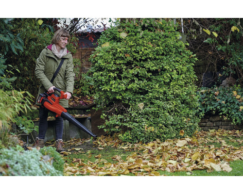 Kvinna använder en Einhell sladdlös lövblås i trädgården