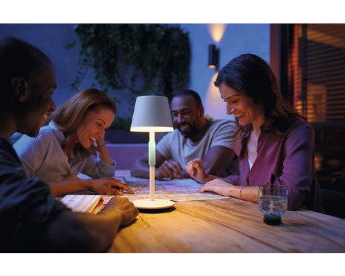 En grupp människor sitter vid ett bord med en bärbar lampa och en karta.