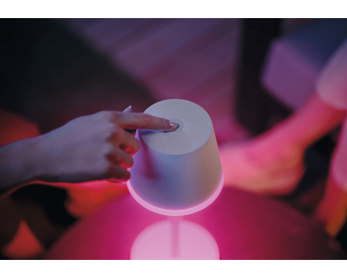 En hand rör en bordslampa som avger ljus