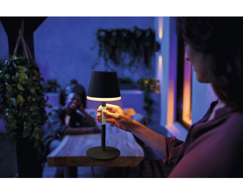 Person som håller en svart bordslampa utomhus.