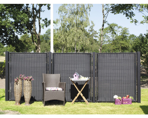 Trädgårdsscen med insynsskydd, rottingfåtölj och trädgårdsbord