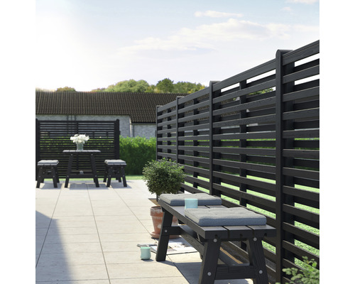 Trädgårdsscen med insynsskydd, bänk och bordgrupp i trä