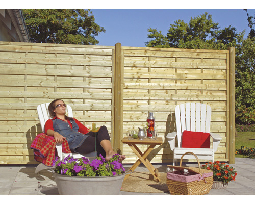 Trädgård med trästaket och avslappnad person i vilstol