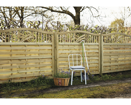 Trästaket med dekorativ finish, trädgårdsstol och växtkorg i trädgården