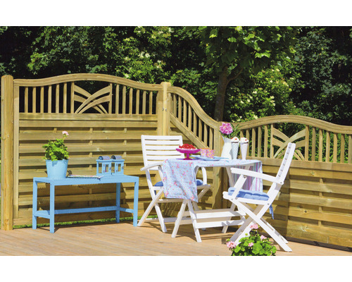 Trädgårdsscen med trästaket, trädgårdsbord och trädgårdsstolar