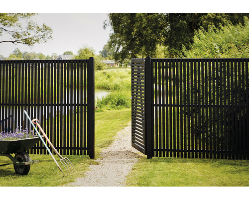 Trädgårdsscen med öppet vertikalt staket och skottkärra