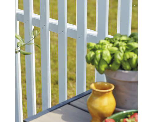 Närbild av ett vitt trädgårdsstaket med dekorativa element på ett bord